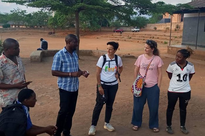 Chipangula Dube stands talking with visiting partners and players beside the ground at the end of the day.