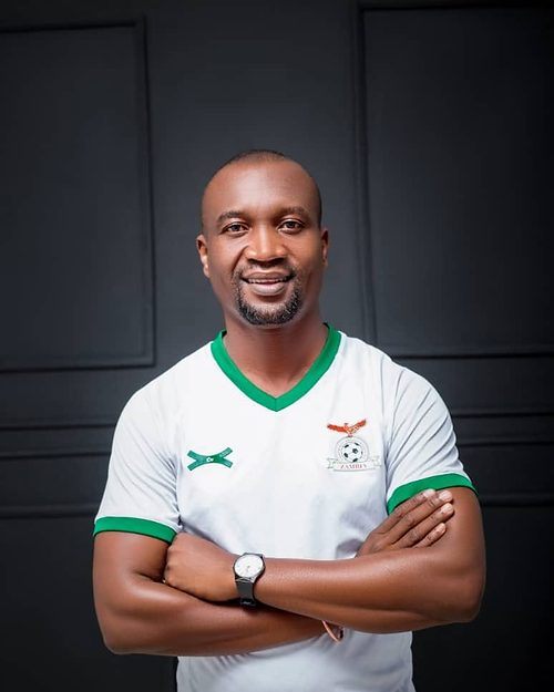 Chipangula Dube, founder and club director of Chipata Girls FC, arms folded, in a Zambia national team shirt.